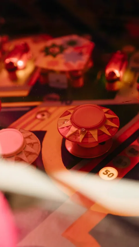 Close-up of vintage pinball machine pop bumpers under warm red light