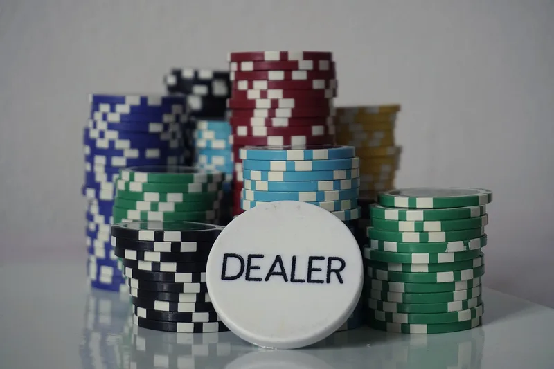 Stacks of poker chips in several colours with a white DEALER button resting in front