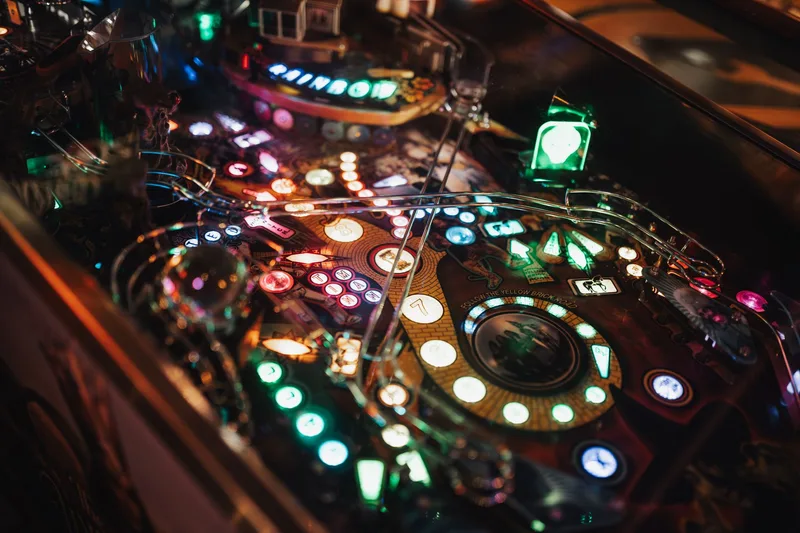 Close-up of pinball playfield with pegs and lights illustrating Plinko board physics