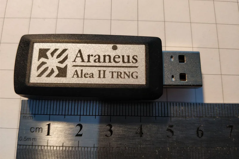 Araneus Alea II, a USB hardware true random number generator, photographed on graph paper beside a ruler