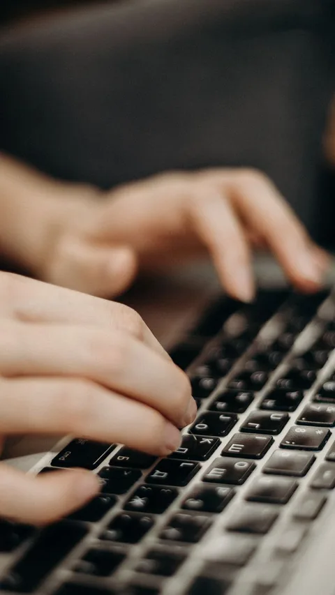 Hands tapping modern laptop keyboard