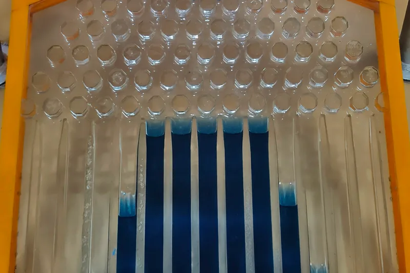 A Galton board: clear hexagonal pegs above vertical channels, with the balls stacked in columns of different heights